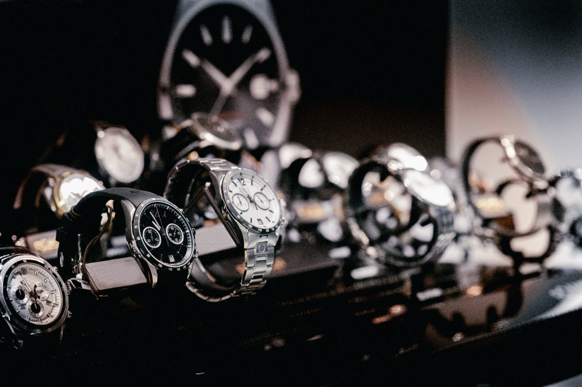 A row of men's watches displayed on stands under low light
